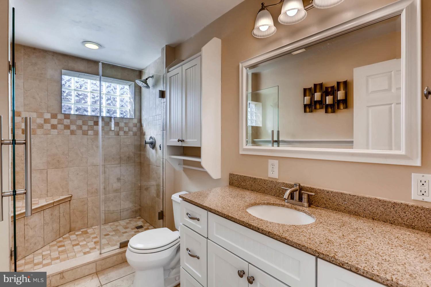 2406 Old Frederick Road Baltimore, MD 21228 - Photo 10 of 25 a bathroom with a granite countertop sink toilet mirror and shower