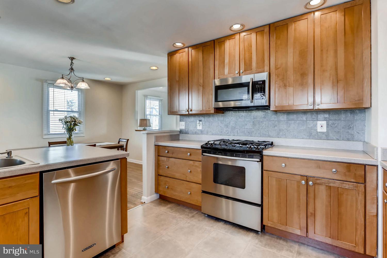 2406 Old Frederick Road Baltimore, MD 21228 - Photo 8 of 25 a kitchen with kitchen island granite countertop wooden cabinets and a stove top oven