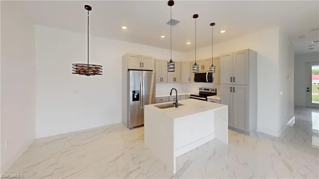 a large kitchen with stainless steel appliances kitchen island a refrigerator a sink a oven and a window