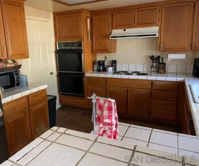 43982 Highlander Drive Temecula, CA 92592 - Photo 8 of 14 a kitchen with stainless steel appliances kitchen island granite countertop a refrigerator sink and cabinets