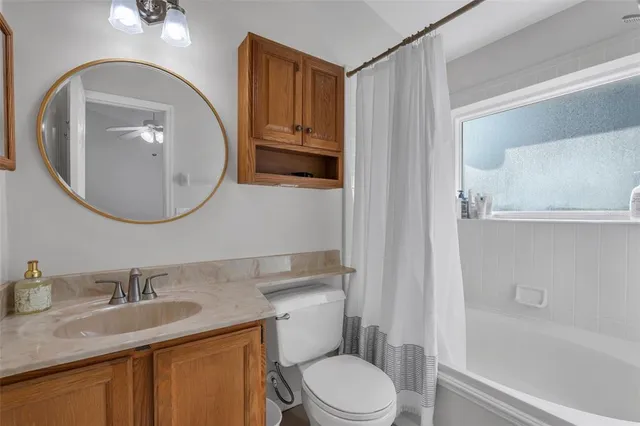 a bathroom with a granite countertop toilet sink and mirror