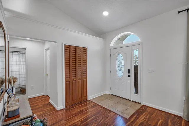an empty room with wooden floor mirror and windows