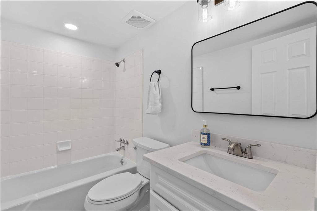 1150 Collier Road Northwest, Unit A1 Atlanta, GA 30318 - Photo 17 of 27 a bathroom with a granite countertop sink toilet a mirror and shower