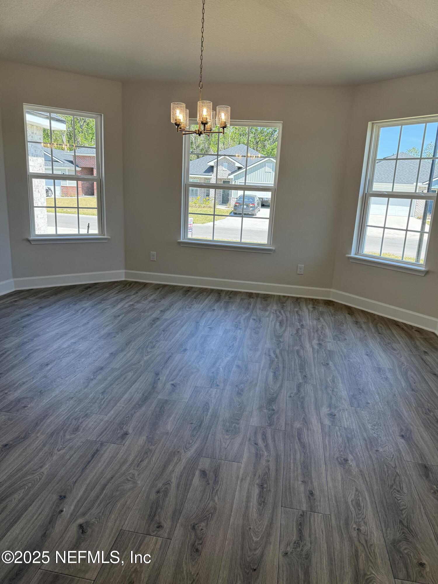 8278 Helmsley Boulevard Jacksonville, FL 32219 - Photo 6 of 27 an empty room with wooden floor chandelier and windows