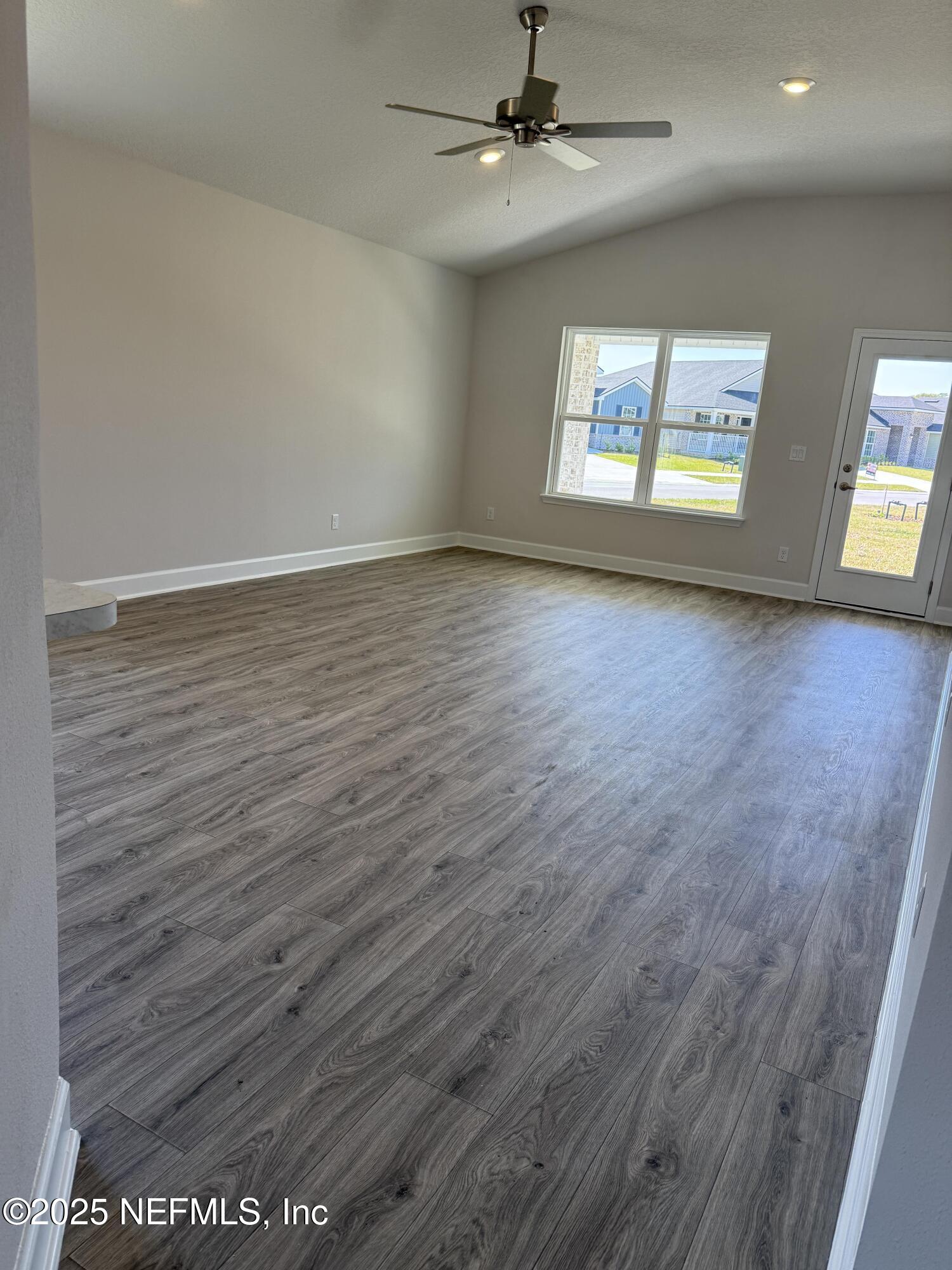 8278 Helmsley Boulevard Jacksonville, FL 32219 - Photo 8 of 27 an empty room with wooden floor chandelier and windows