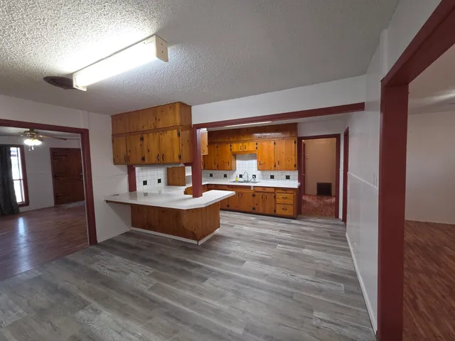 a view of kitchen island with stainless steel appliances furniture large window and wooden floor