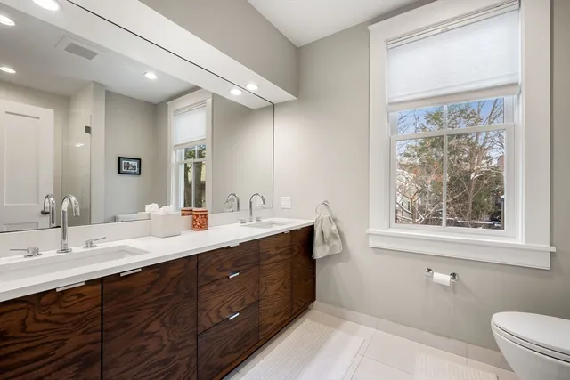 a bathroom with a double vanity sink toilet and a mirror