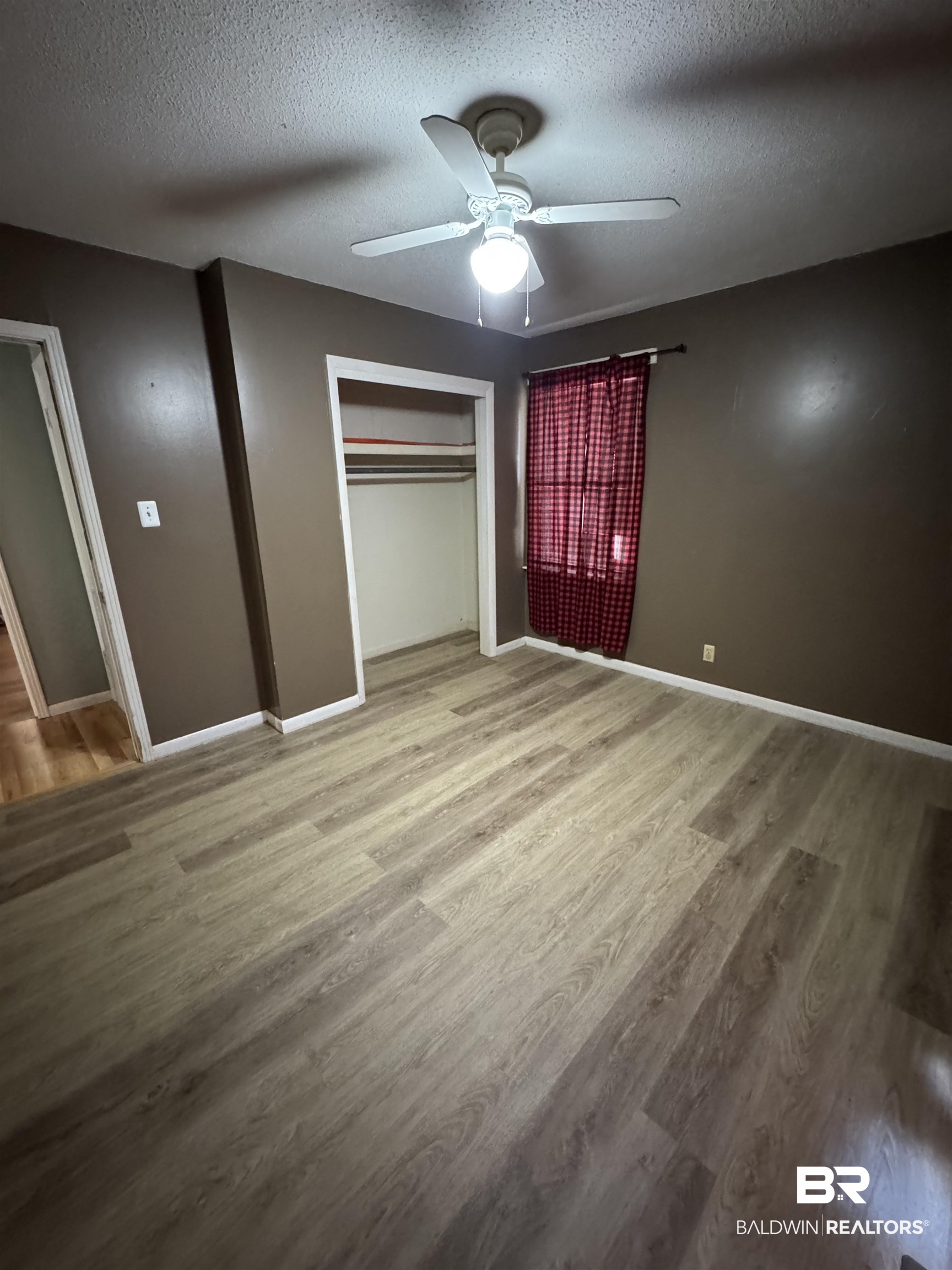 8065 Middle Ring Road Mobile, AL 36619 - Photo 19 of 21 Unfurnished bedroom featuring baseboards, a textured ceiling, and wood finished floors