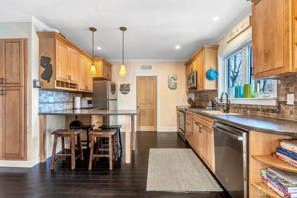 387 Prospect Avenue Dunellen, NJ 08812 - Photo 6 of 34 a kitchen with stainless steel appliances granite countertop wooden floor a dining table and chairs