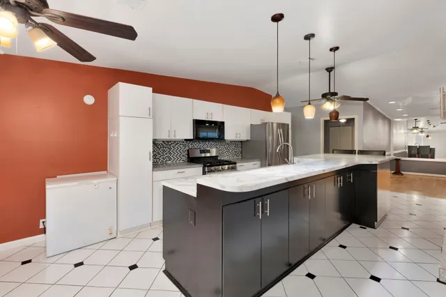 a kitchen with stainless steel appliances granite countertop a sink a stove and a refrigerator