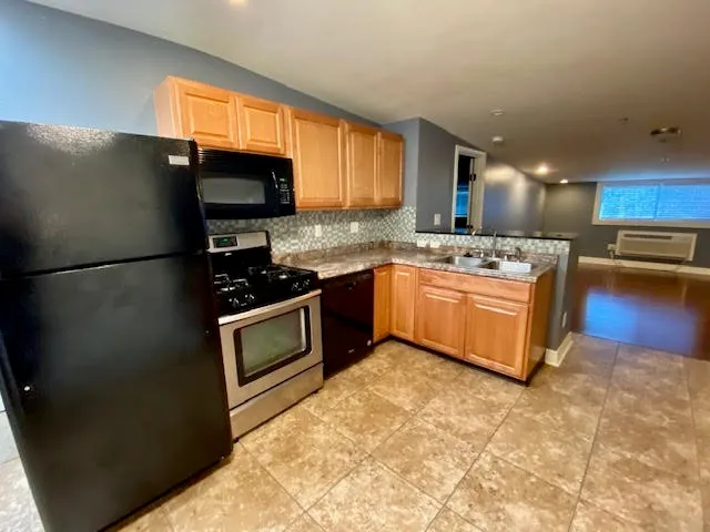 a kitchen with stainless steel appliances granite countertop a refrigerator a stove a sink and a microwave