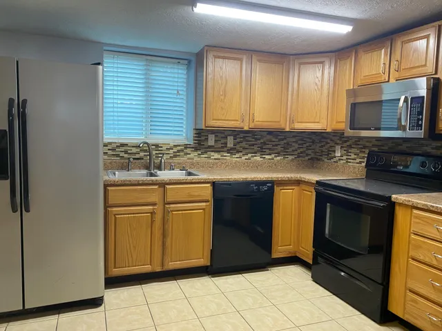 a kitchen with stainless steel appliances granite countertop a stove a sink and a microwave