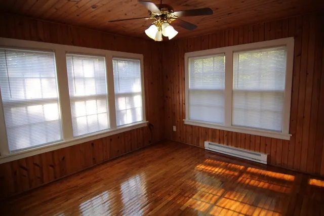 a view of an empty room with wooden floor and a window