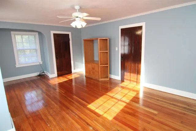 a view of an empty room with window and wooden floor