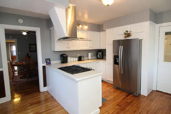 a kitchen with stainless steel appliances granite countertop a refrigerator a sink a stove and wooden floor