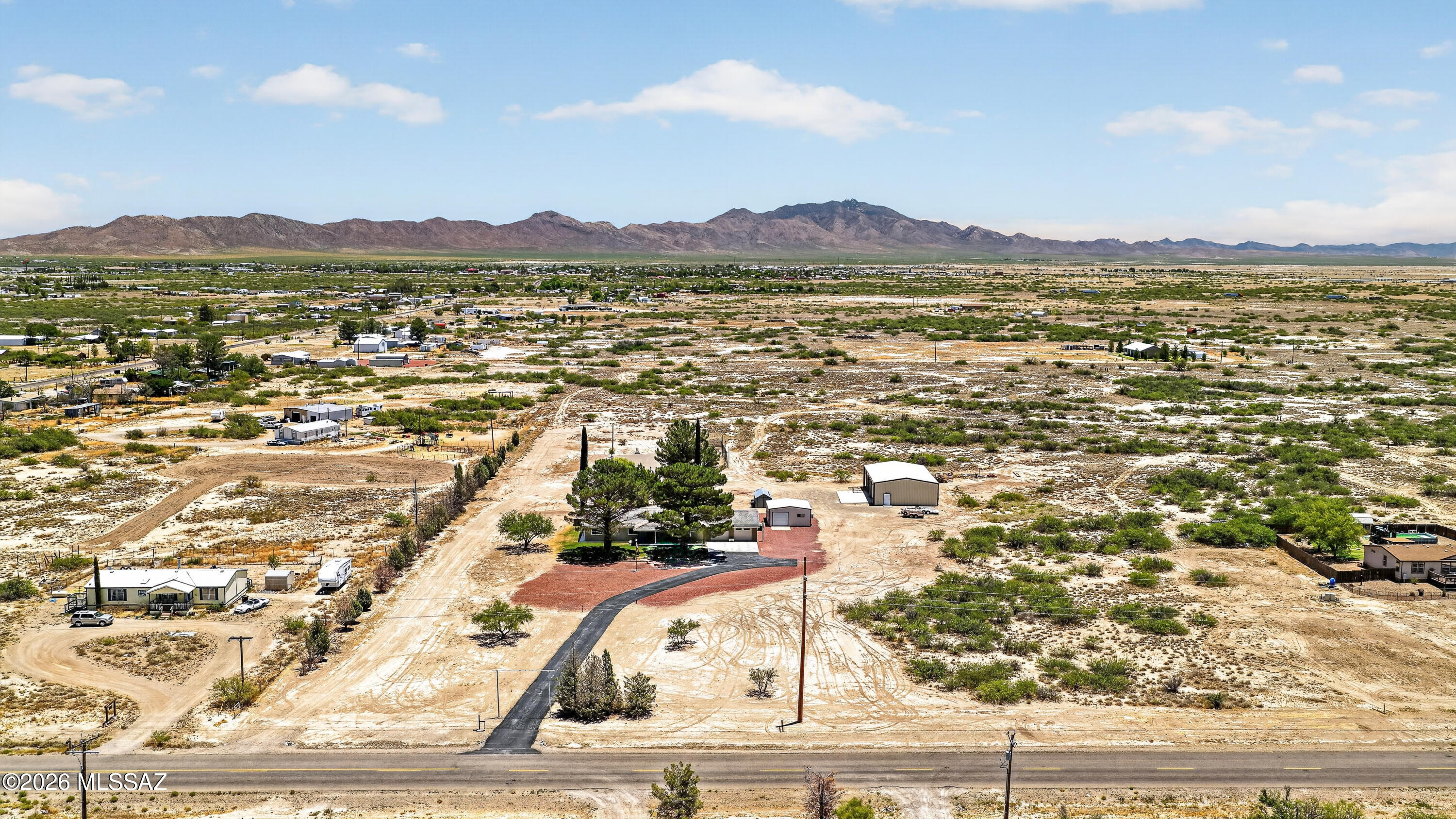 194 Taylor Road Willcox, AZ 85643 - Photo 47 of 54 Aerial views capture the full property layout, including the west-facing home, detached shop and outbuildings, circular driveway, mature trees, and beautiful mountain views.