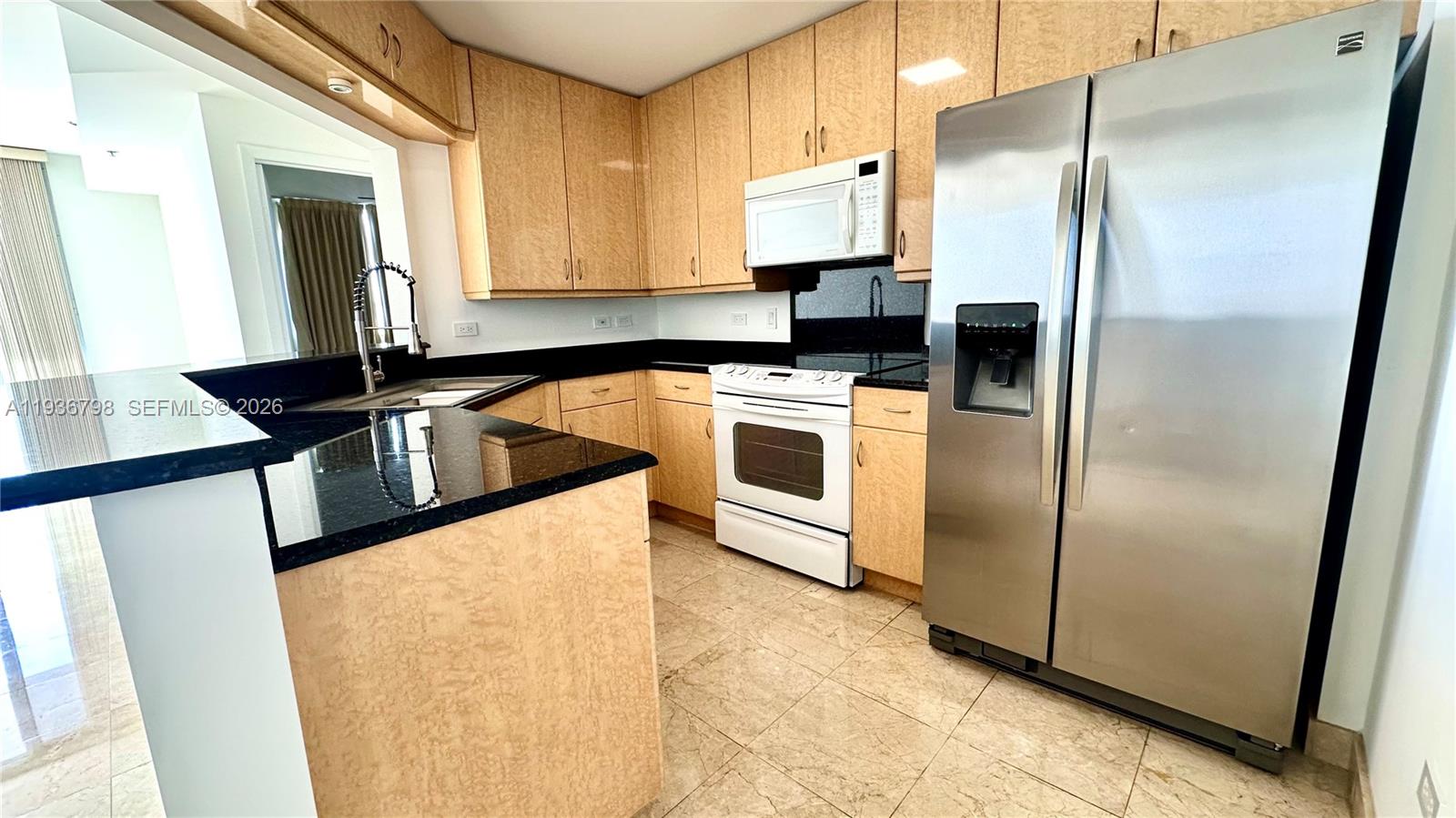 801 Brickell Key Boulevard, Unit 2707 Miami, FL 33131 - Photo 18 of 24 a kitchen with granite countertop a refrigerator and a sink