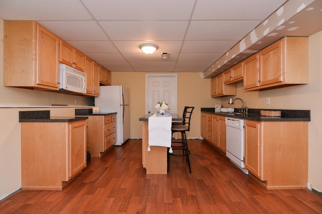 73 Drew Road Derry, NH 03038 - Photo 32 of 42 a kitchen with stainless steel appliances granite countertop a refrigerator a stove top oven a sink dishwasher and white cabinets with wooden floor