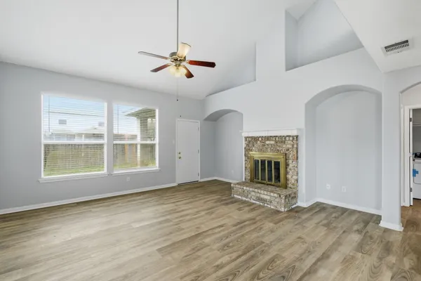 a view of an empty room with a window and wooden floor