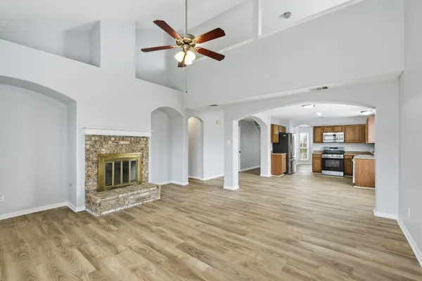 a view of a livingroom with a fireplace a ceiling fan and windows
