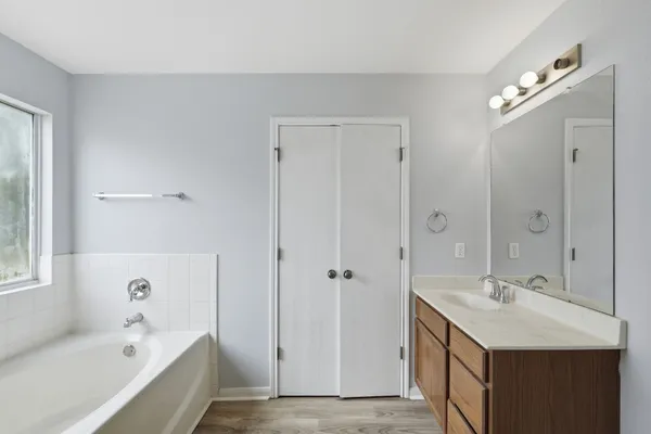 a bathroom with a tub a sink and mirror