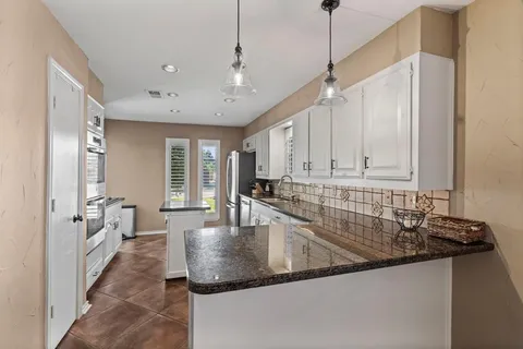 a kitchen with stainless steel appliances granite countertop a sink a oven and a refrigerator with wooden floor