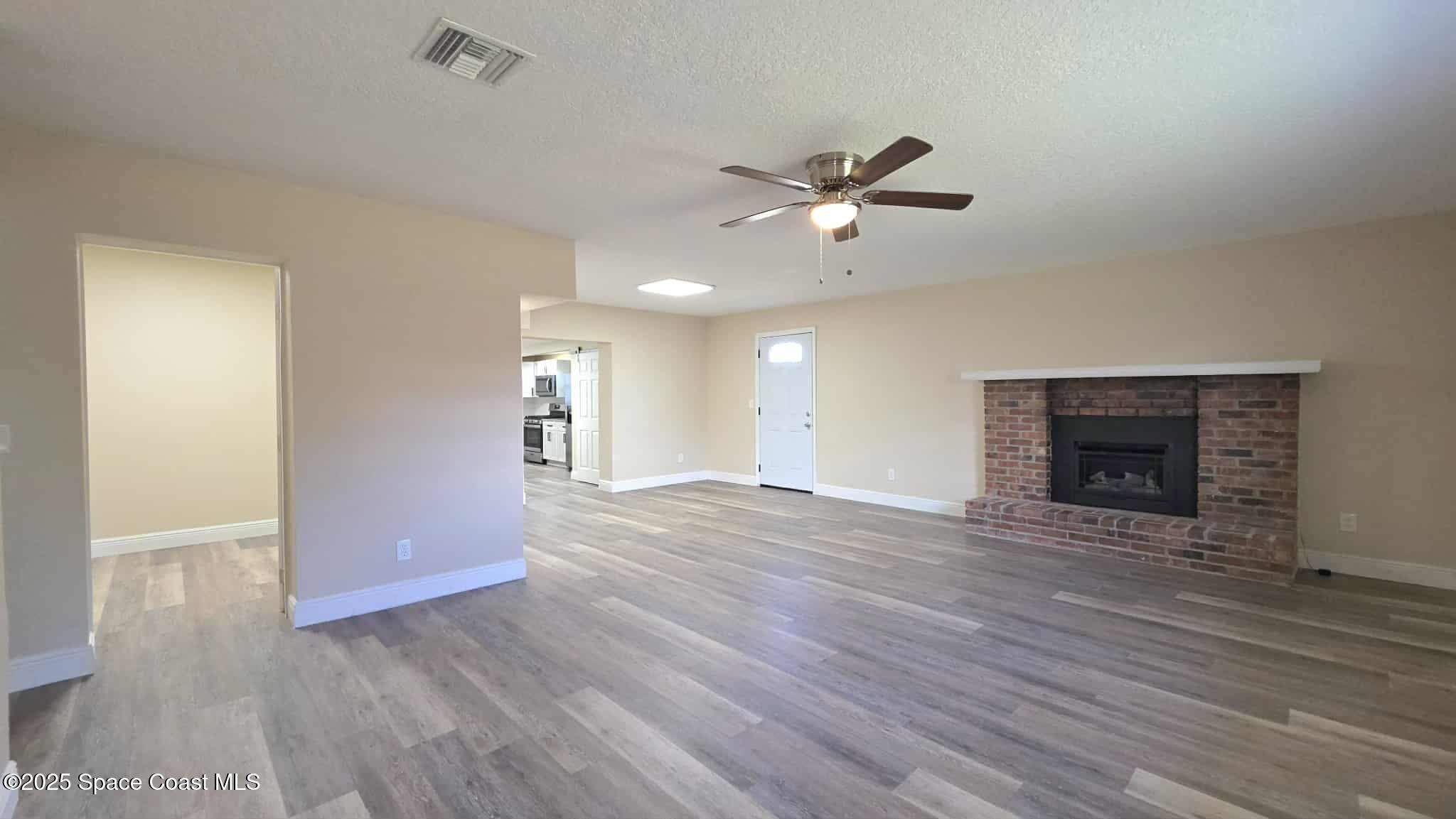 410 4th Street Merritt Island, FL 32953 - Photo 13 of 37 wooden floor in an empty room with a fireplace