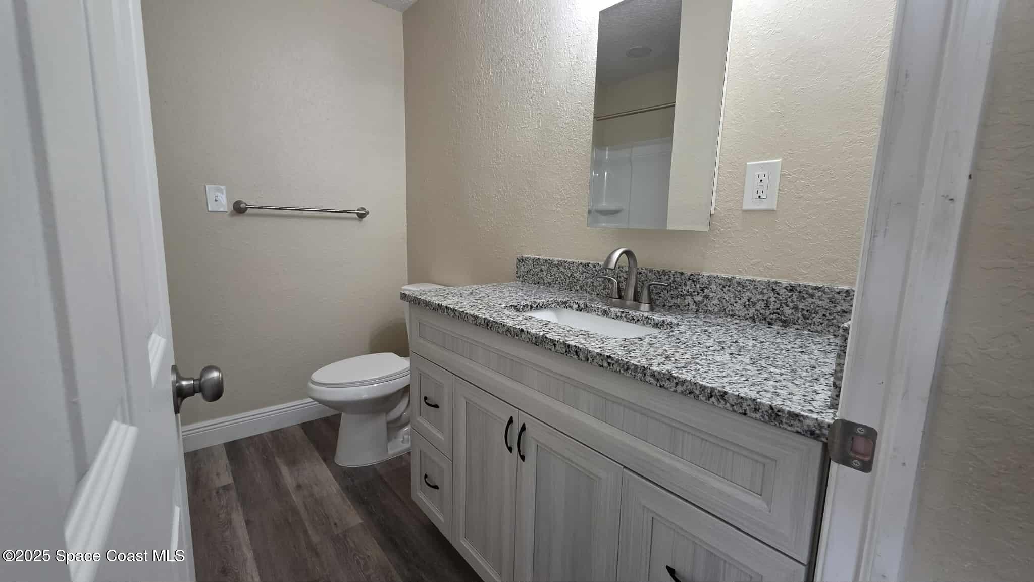 410 4th Street Merritt Island, FL 32953 - Photo 22 of 37 a bathroom with a granite countertop sink toilet and a mirror