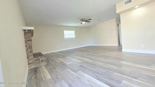 a view of a room that has wooden floor and a window