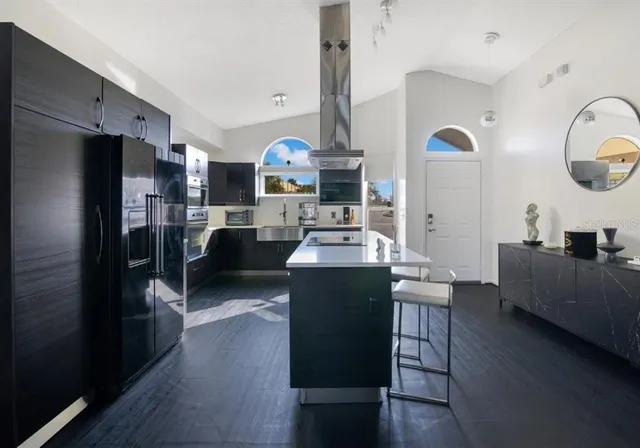 a kitchen with stainless steel appliances kitchen island granite countertop a refrigerator a stove a sink dishwasher and wooden cabinets with wooden floor