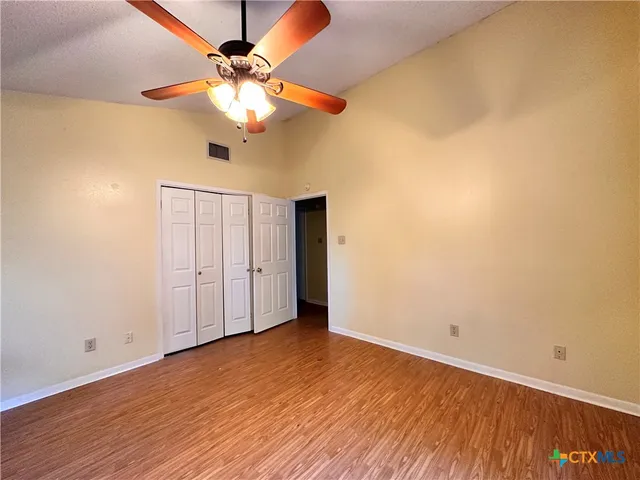 a view of an empty room with window and wooden floor