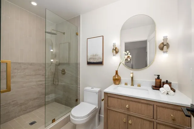 a bathroom with a toilet a sink a glass door a shower a mirror a vanity and vanity