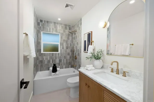 a bathroom with a granite countertop sink mirror vanity bathtub and a toilet