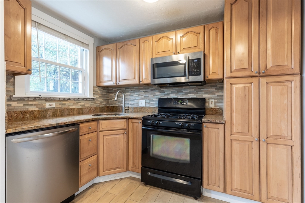 440 Adams Street, Unit 1 Boston, MA 02122 - Photo 8 of 18 a kitchen with stainless steel appliances granite countertop a stove microwave and sink