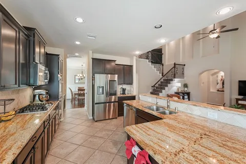 a large kitchen with stainless steel appliances kitchen island granite countertop a sink and a refrigerator