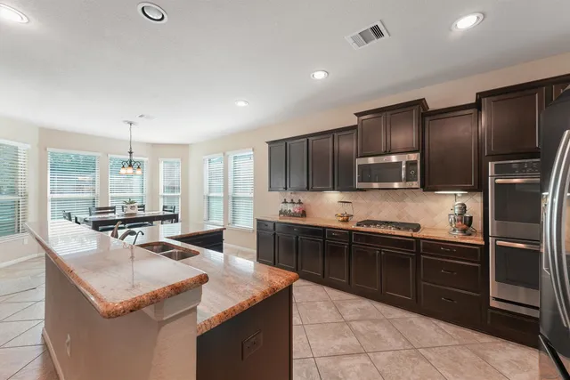 a large kitchen with stainless steel appliances kitchen island granite countertop a sink and a refrigerator