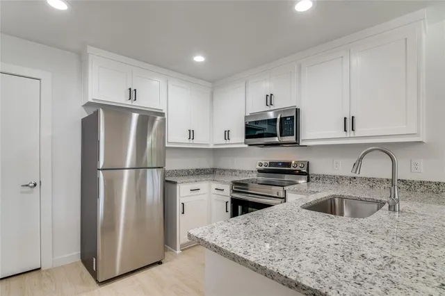 a kitchen with refrigerator a microwave a sink and cabinets
