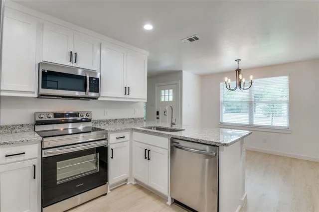 a kitchen with granite countertop a stove top oven microwave and cabinets