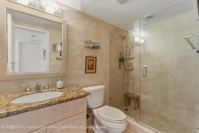 a bathroom with a granite countertop sink toilet mirror and shower