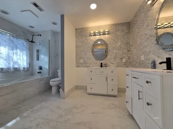 a spacious bathroom with a double vanity sink toilet mirror and bathtub