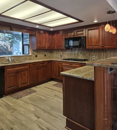 a kitchen with stainless steel appliances granite countertop wooden cabinets a stove top oven a sink and dishwasher