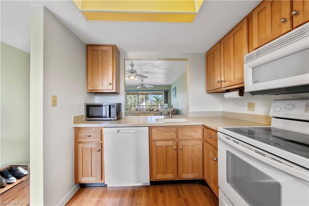 1018 Manatee Road, Unit E302 Naples, FL 34114 - Photo 4 of 19 Kitchen with white appliances, light wood-type flooring, light countertops, ceiling fan, and brown cabinetry