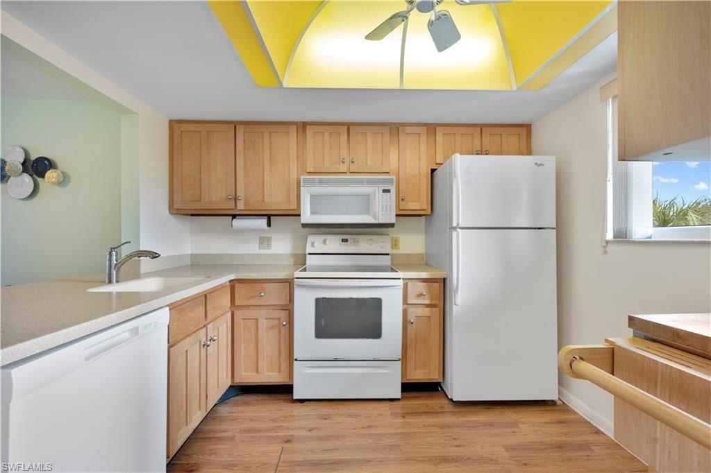 1018 Manatee Road, Unit E302 Naples, FL 34114 - Photo 5 of 19 Kitchen with white appliances, light countertops, a ceiling fan, and light wood-style floors