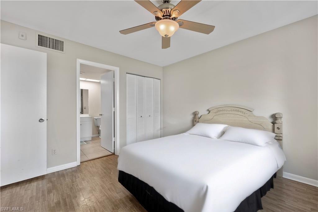 1018 Manatee Road, Unit E302 Naples, FL 34114 - Photo 10 of 19 Bedroom with wood finished floors, a closet, ensuite bath, and a ceiling fan