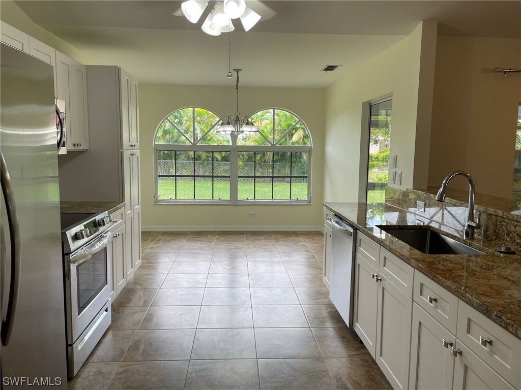 5727 Rose Garden Road, Unit B Cape Coral, FL 33914 - Photo 11 of 26 a large kitchen with granite countertop a sink window and cabinets