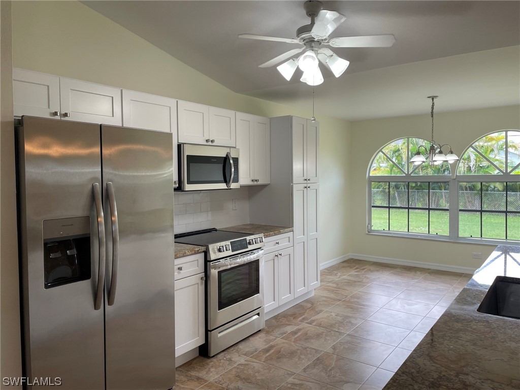 5727 Rose Garden Road, Unit B Cape Coral, FL 33914 - Photo 12 of 26 a kitchen with stainless steel appliances granite countertop a refrigerator a stove a microwave oven with cabinets and wooden floor