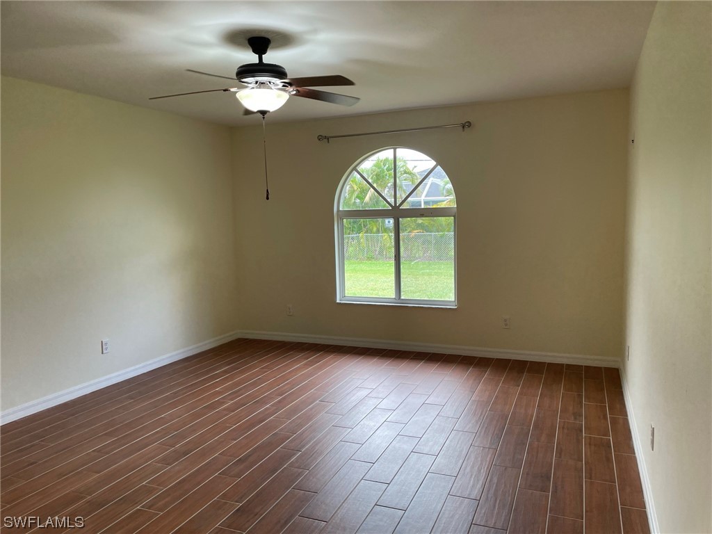 5727 Rose Garden Road, Unit B Cape Coral, FL 33914 - Photo 15 of 26 an empty room with wooden floor chandelier fan and windows