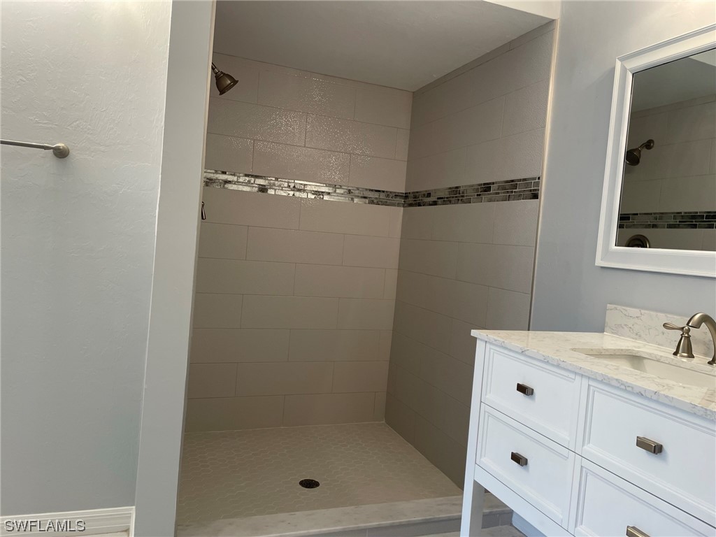 5727 Rose Garden Road, Unit B Cape Coral, FL 33914 - Photo 19 of 26 a bathroom with a shower sink vanity and mirror