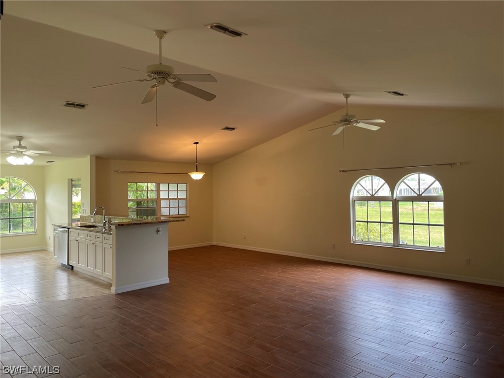 5727 Rose Garden Road, Unit B Cape Coral, FL 33914 - Photo 2 of 26 an empty room with wooden floor a kitchen view and a window