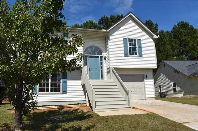 a view of a house with a yard and large tree